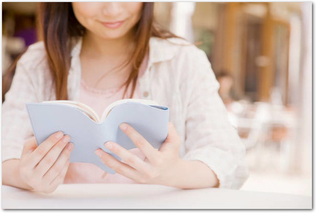カフェで本を読む笑顔の女性